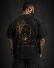 Person wearing a black t-shirt with a graphic design and text on the back against a dark background