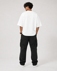 Person wearing a white oversized t-shirt and black cargo pants on a plain background