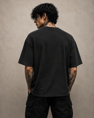 Person wearing a black t-shirt and pants against a beige background