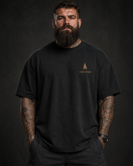 Man wearing a black t-shirt with a logo on a dark background